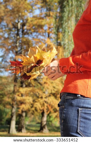 Young woman with bouquet of colorful autumn leaves
