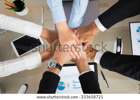 High Angle View Of Businesspeople Stacking Hands In Office Royalty-Free Stock Photo #333658721