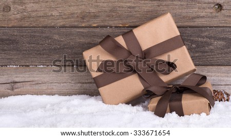 Two brown gift packages on snow against a rustic wood background with copy space