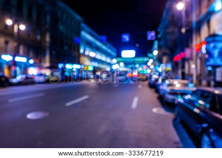Nights lights of the big city, night avenue in the light of lanterns and illuminated shop windows. Wide-angle view, defocused image, in blue tones