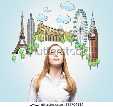 A beautiful woman is looking up by dreaming about the visiting of the most famous places in the world. The concept of tourism and sightseeing. Light blue background.