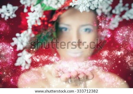 Christmas winter woman with tree hairstyle and makeup for holiday night. Fairy blowing magical glitter, stardust. Beauty fashion model with white lips and red background. New Year. Instagram edition