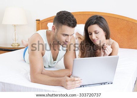 Smiling couple in the bed with notebook whatching movie
