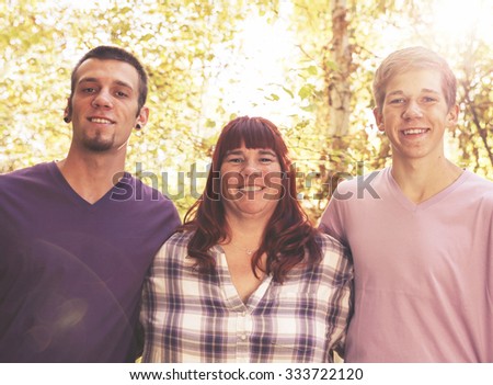 a cute family posing for a photo in a park setting with trees in the background toned with a retro vintage instagram filter effect app or action 