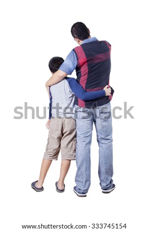 Rear view of a young father and his son embracing each other while looking at copy space in the studio