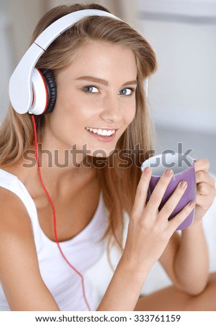 Portrait of beautiful woman in morning listening music sitting on bed at home