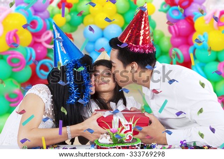 Portrait of happy girl celebrate her birthday and get a birthday gift with kiss from her parents