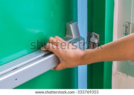 Hand is pushing/opening the emergency fire exit door Royalty-Free Stock Photo #333769355