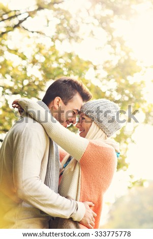 A picture of a young romantic couple hugging in the park in autumn