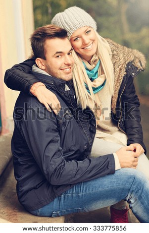 A picture of a young romantic couple sitting in the park in autumn