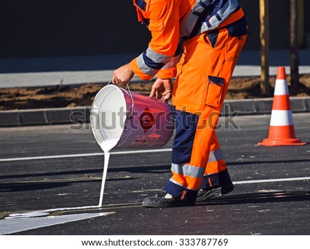 Man is painting road signs on the asphalt in the city street