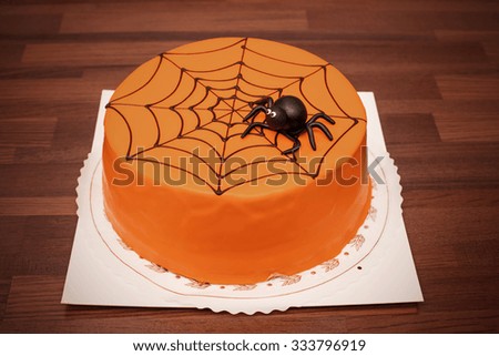 Orange children's birthday cake with black spider decoration in Finland. Focal point is the spider. Image includes a effect.