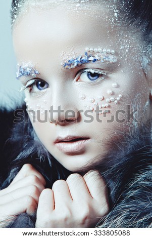 Winter Woman Portrait. Snow. Beauty Fashion Model Girl with White Hair and Blue Eyes closeup. In a fur coat.