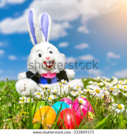 Beautiful view of colorful Easter eggs with funny Easter bunny in the background lying in the grass on a sunny day
