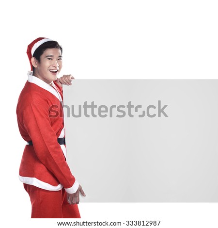 Young man in Santa Claus costume behind white board with space for text over white background