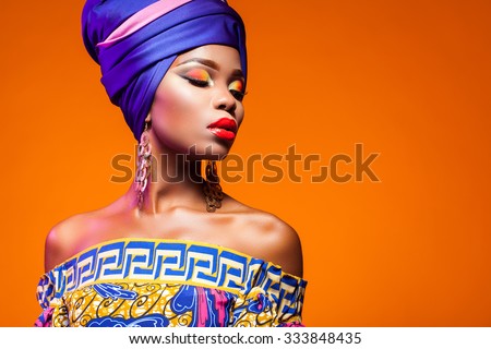 African woman in a bright dress on orange background Royalty-Free Stock Photo #333848435