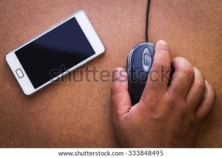 Computer mouse hand man beside mobilephone on wooden