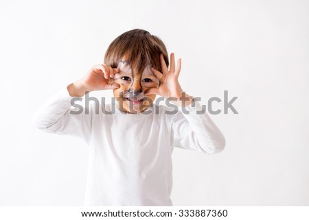 Cute boy with painted face as a lion, having fun, studio shot