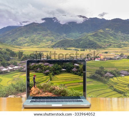 Conceptual image of a computer laptop on Traveler take picture at Rice fields on terraced of Tu le District, YenBai province, Northwest Vietnam