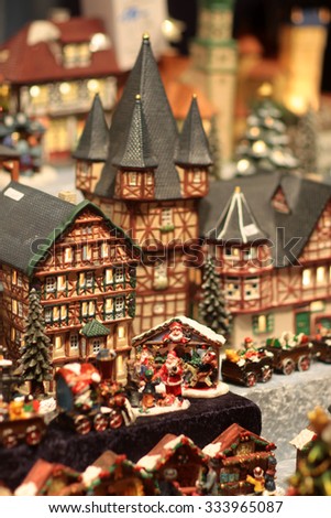 Picture of little toy town with festive houses with lights in windows santa claus and reindeers figures and toy trains, vertical picture