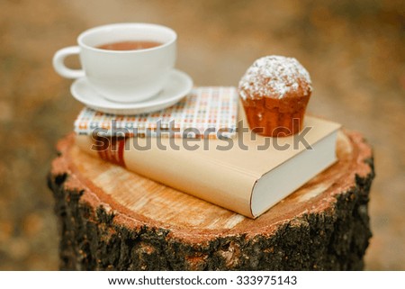 Cup of tea, stack of books with autumn leave on wooden background
