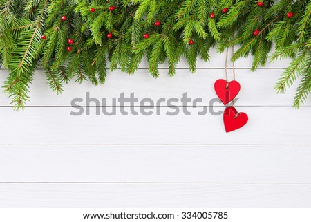 Christmas background. Christmas fir tree with red hearts decoration on white wooden board background with copy space. 