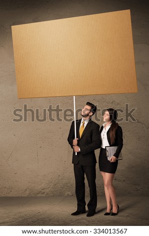 Young business couple holding a blank cardboard