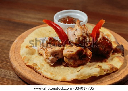 Beautifully submitted roasted meat with peppers, pita and sauce on wooden tablet. Traditional Oriental food. Myasne delicious and nutritious meal. Photo for culinary magazines, backdrops and websites.