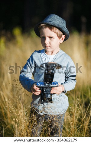 Stylish small boy with retro camera photographing outdoors on sunny autumn day