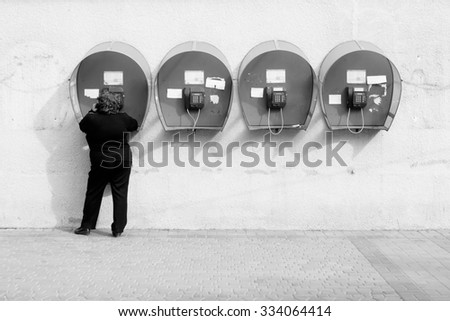 Woman talking on pay phone. Four payphones on city street. Means of communication. Black and white photo
