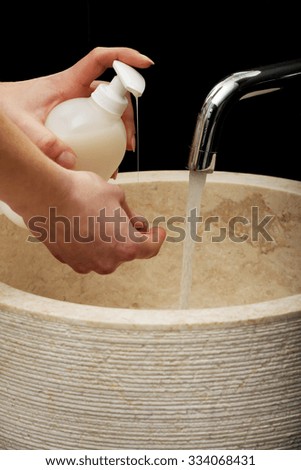 Woman cleaning hands in bathroom.