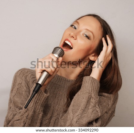 Happy singing girl. Beauty woman  with microphone over white background. 