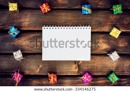 Boxes with gifts on a dark wooden boards. White notepad. Happy new year. Space for text. Old background. New Year background. Christmas. Xmas. Noel.