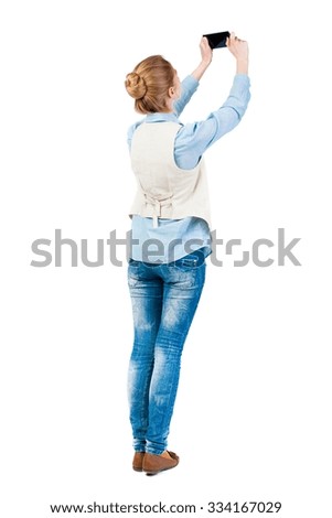 back view of standing young beautiful  woman  in vest and using a mobile phone. girl  watching. Rear view people collection.  backside view of person.  Isolated over white background. 