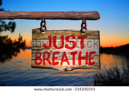Just breathe motivational phrase sign on old wood with blurred background