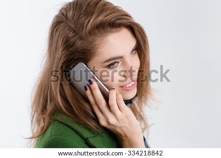 Closeup portrait of a smiling young woman talking on the phone isolated on a white background