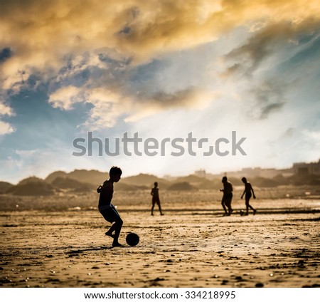 Silhouette of  the boy on the beach with a ball at sunset