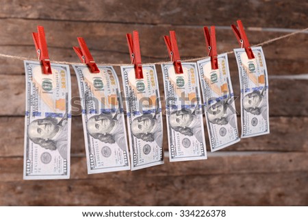 Concept of money laundering - dollars are drying on cord on wooden background