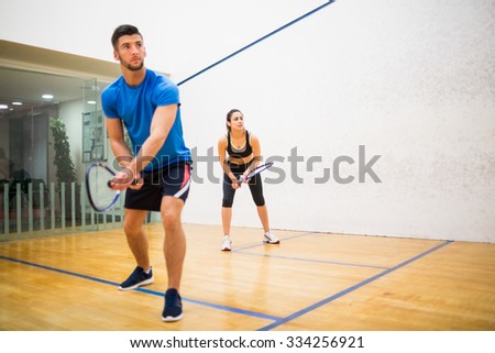 Couple play some squash together in the squash court Royalty-Free Stock Photo #334256921
