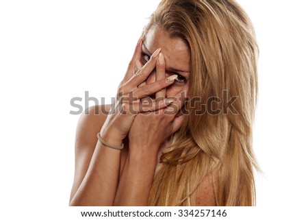 Ashamed smiling young woman looking through her fingers