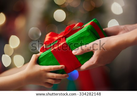 Hands of parent giving a Christmas gift to child.