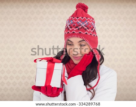 Content brunette in winter clothes holding gift against room with wooden floor