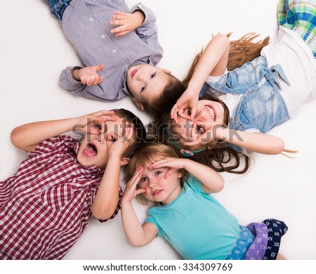 children lying on the floor with hands imitating glasses isolated on white background