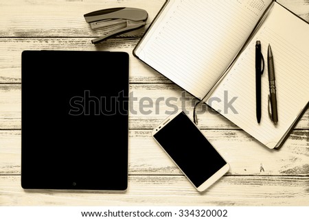 Modern workplace with laptop, pens, smartphone, notepad and stapler on white wooden vintage table retro filtered