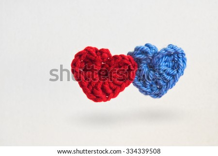 Two hand made crochet knit Red Heart and Blue Heart on white background. Valentines Day, Wedding composition with hearts.