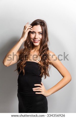 young beautiful stylish girl in a black business dress and sunglasses standing on a white background with a snow-white smile, smiling
