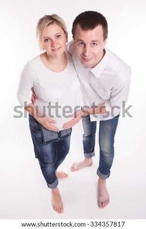 Pregnant young blonde in a white T-shirt and jeans and a guy in jeans and a white shirt on a white background, photographed from above picture with depth of field
