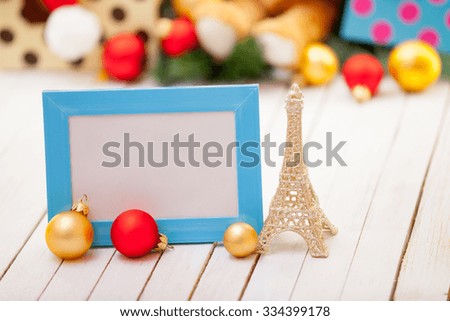 Photo frame with Eiffel tower toy and christmas gifts on background