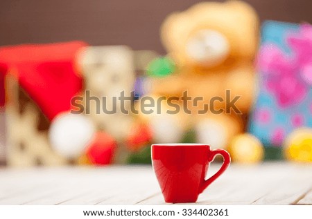 Cup of tea or coffee with christmas gifts on background