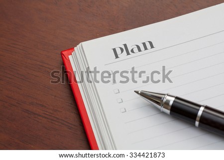 Conceptual,notebook on a wooden table. open diary and pen with plan word